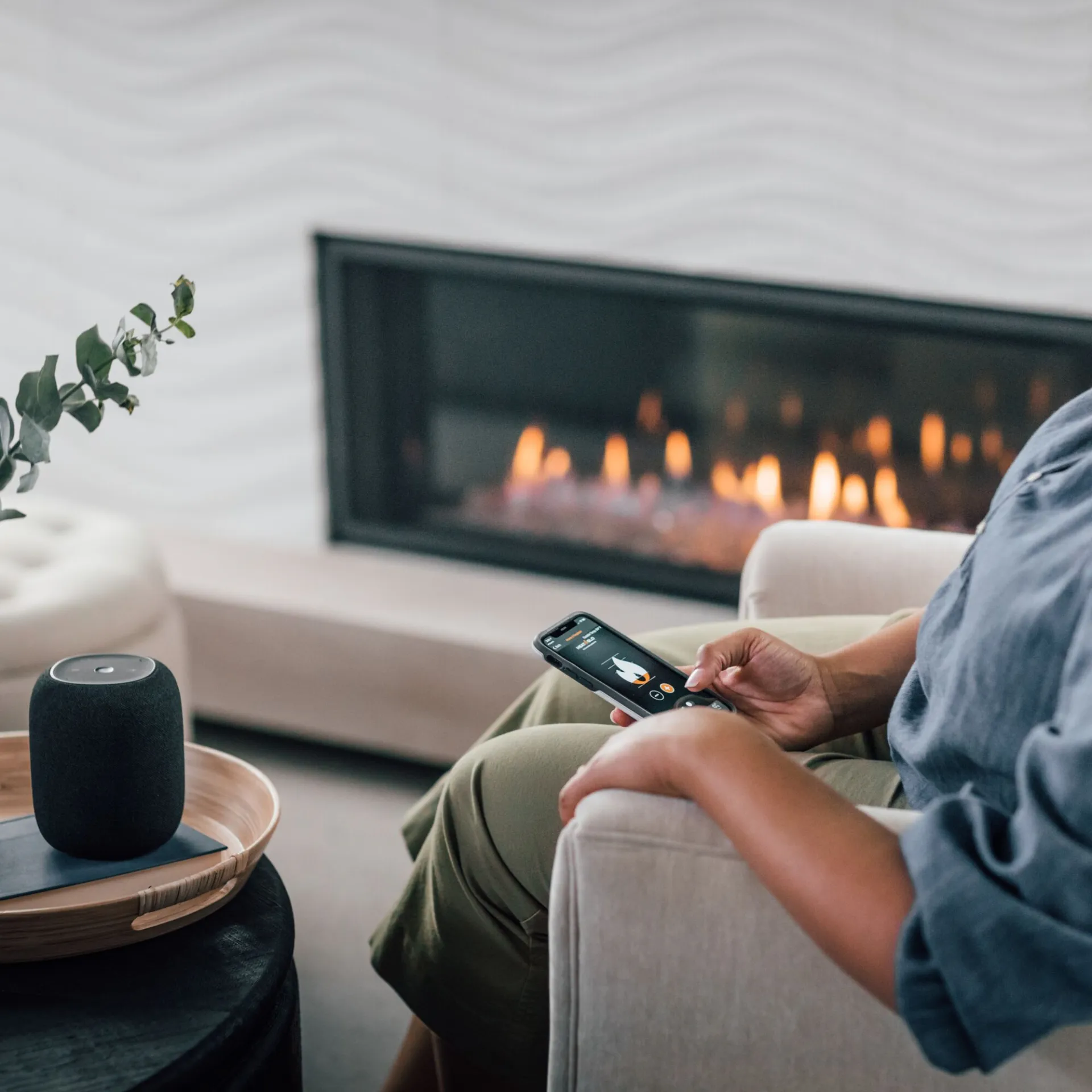 Homeowner adjusting a modern linear gas fireplace from a smartphone