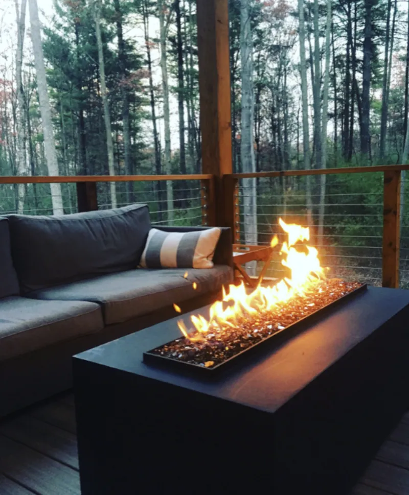 Acucraft outdoor fire table on wooden deck surrounded by trees