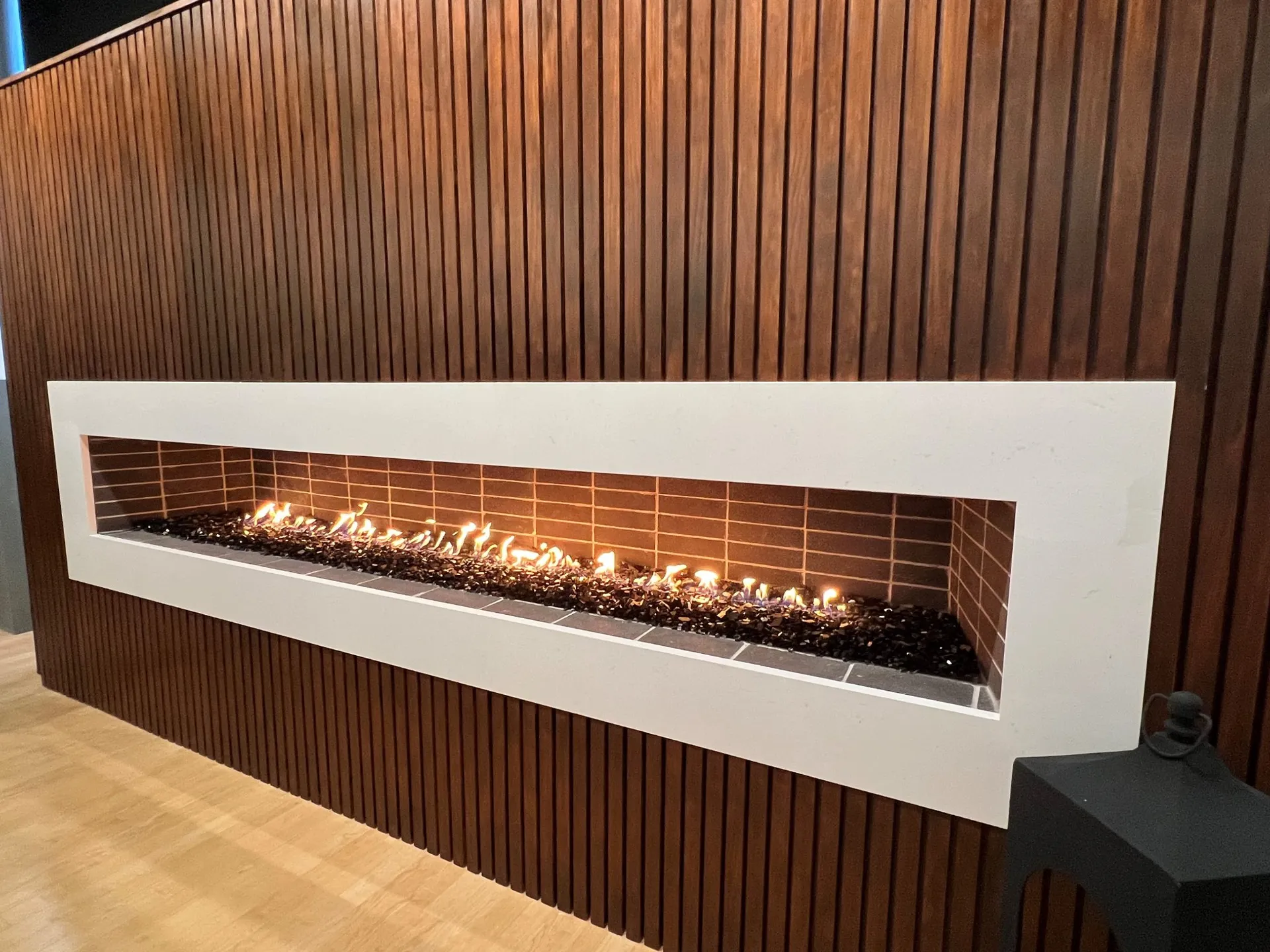 Isokern Maximus Linear fireplace with sleek modern design against wood panel wall