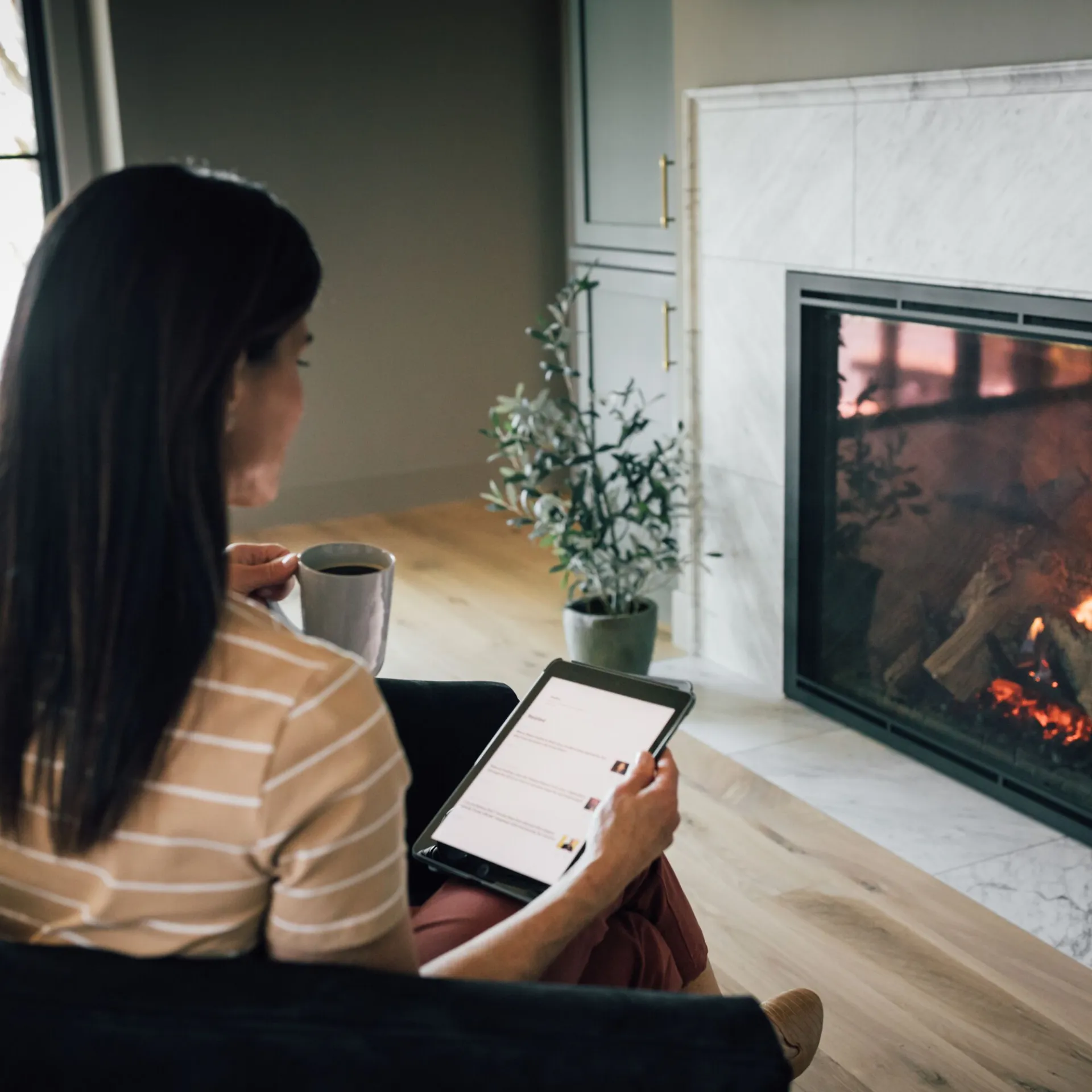Person relaxing by a fireplace with a tablet